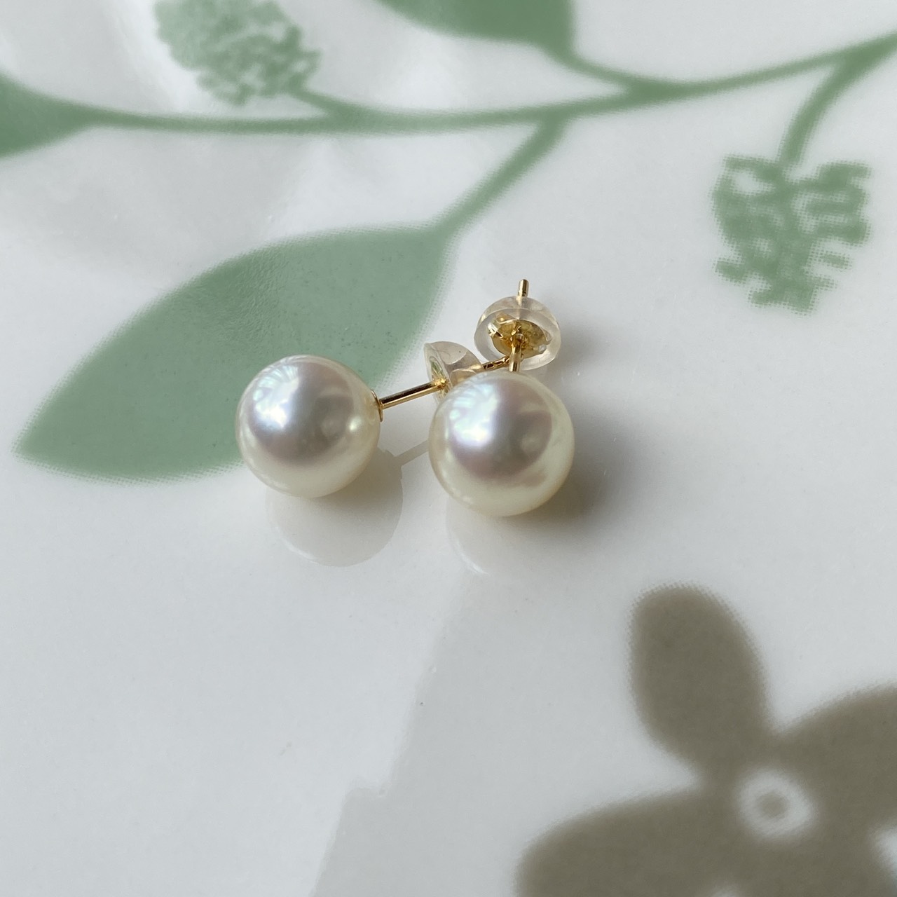 Yuyake round Akoya pearl earrings on a green leaf pattern