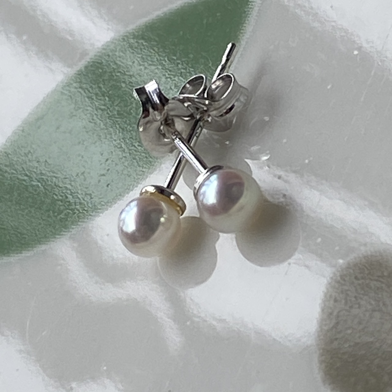 Tiny Baby Akoya pearl stud earrings photographed close up