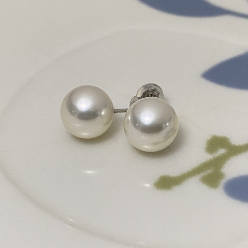 Natural white 9mm Akoya pearl stud earrings on a patterned dish