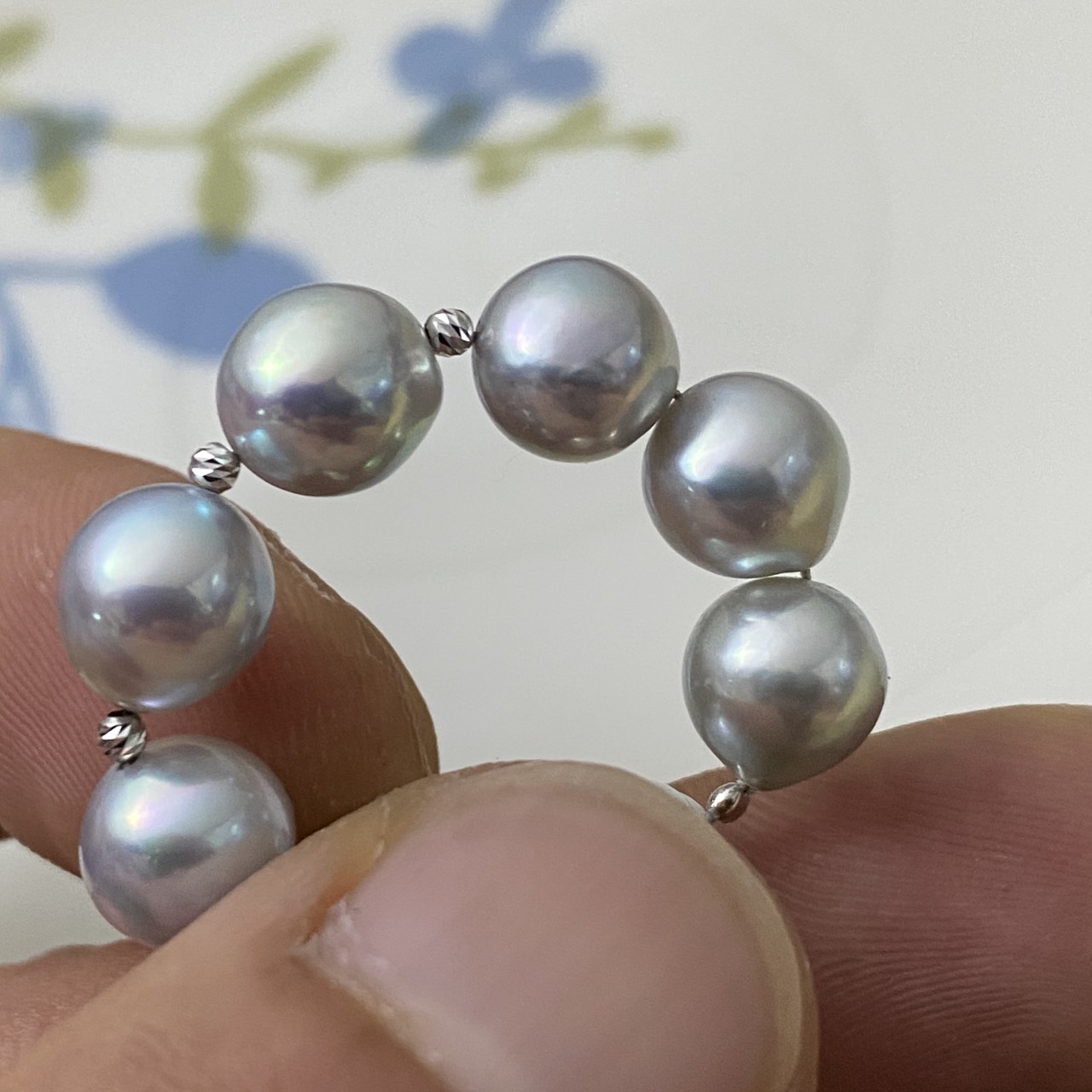 Natural blue Akoya pearl ring held between fingers showing its circular form