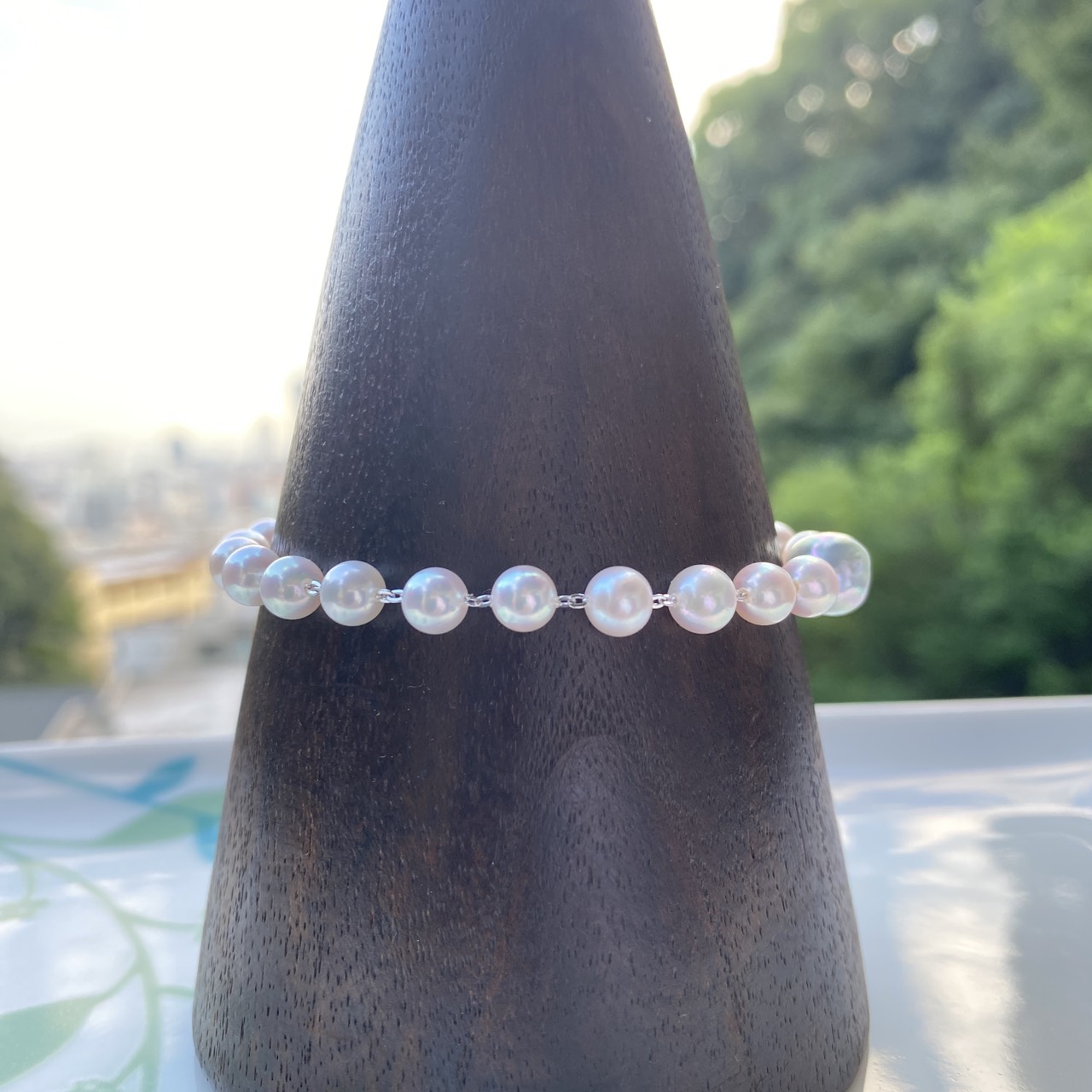 Row of lustrous white-pink Akoya pearls linked with silver chain