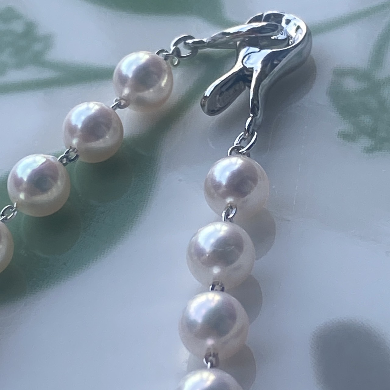Close-up of the clip clasp and individually linked white-pink Akoya pearls