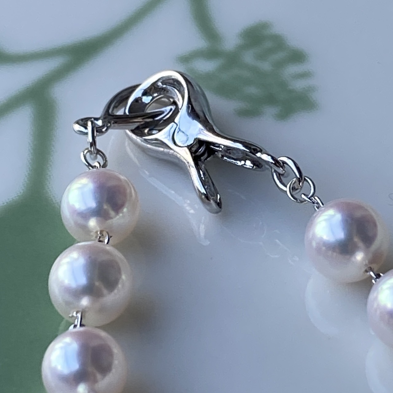 Macro view of the sterling silver clip-style clasp and adjacent Akoya pearls.